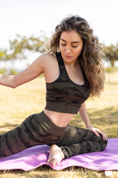 Frau in Yoga-Pose mit langen lockigen Haaren, natürliche Schönheit bei Tageslicht, gesunder Lebensstil mit körperlicher Aktivität zum Entspannen - Foto, Bild