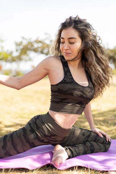 pose de yoga de mujer con cabello largo, belleza natural a la luz del día, estilo de vida saludable con actividad física para relajarse en el parque - Foto, Imagen