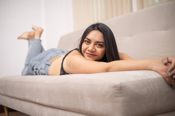 lying face down stretching and smiling beautiful young latin woman with long hair, lifestyle and natural beauty in studio - Foto, Bild