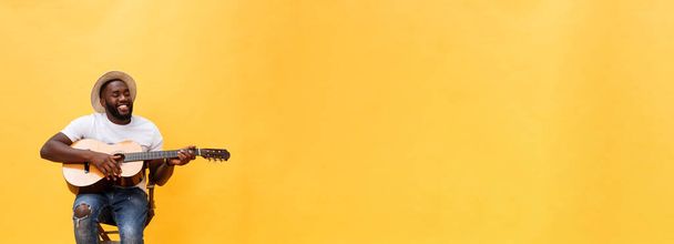 Полнометражное фото взволнованного артиста, играющего на гитаре в непринужденном номере. Изолированный на желтом фоне
 - Фото, изображение