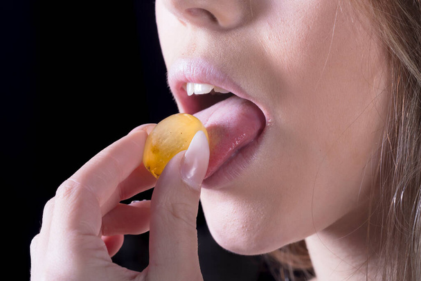 портрет молодой женщины положить желтый виноград на ее полные губы сексуально портрет женщины и пищи - Фото, изображение