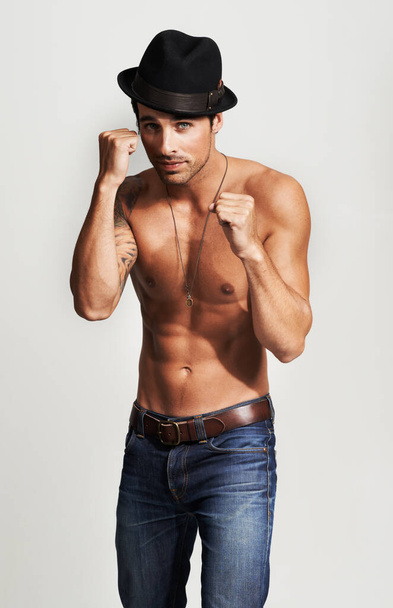 Ready for a fight. Portrait of shirtless young man wearing a hat and posing in a fighting stance - Фото, изображение