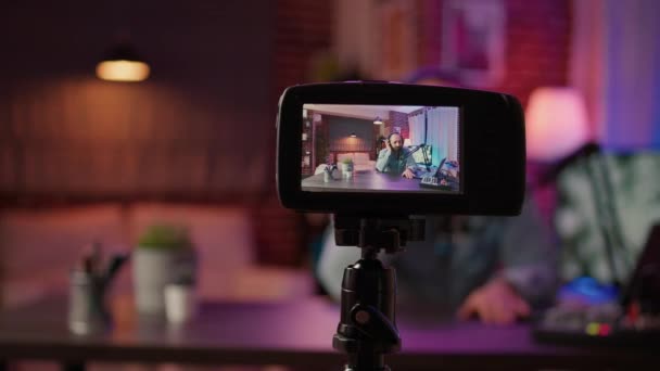 Selectieve focus op digitale videocamera scherm opname mannelijke vlogger met hoofdtelefoon praten op microfoon in huis podcasting studio. Sluiten van dslr filmen influencer streaming live internet show. - Video