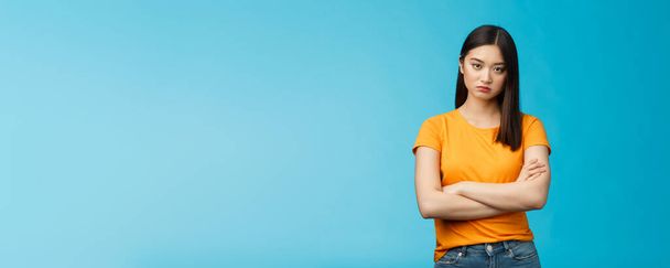 Serious-looking indifferent and upset intense asian woman brunette, cross arms chest look strict ignorant, pissed listening nonsense, annoyed stupid conversation, stand blue background. - Photo, image