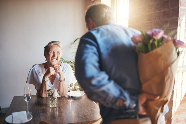 Elderly, couple and flowers on a date for surprise, love and romance in their house. Senior woman, man and retirement together with bouquet to celebrate marriage, birthday or anniversary in the home. - Foto, Bild