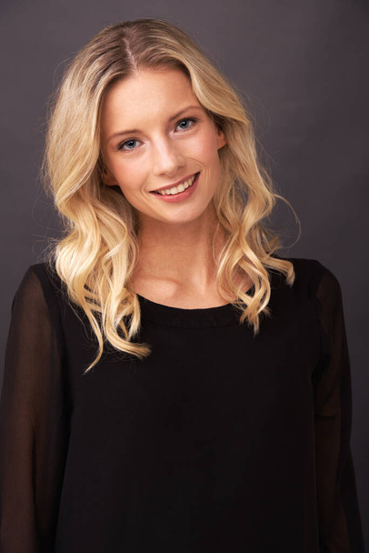 An elegant kind of beauty. Portrait of a beautiful young blonde woman smiling sweetly in studio - 写真・画像