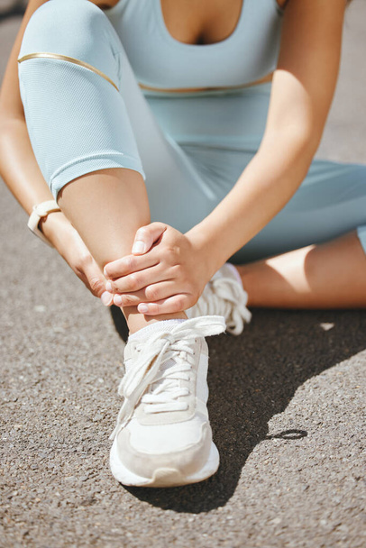 Sports, injury and fitness ankle pain during exercise, running and training outside with muscle or joint. Woman, risk and hurt hands athlete holding broken leg bone with bad bruise in the street. - Fotoğraf, Görsel