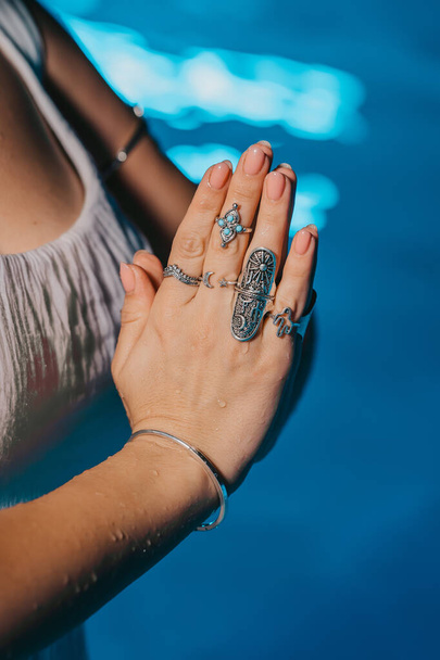 Woman holding namaste in clean water. Palms with gypsy boho rings. Meditation, praying, gratitude, purity background. . High quality photo - Фото, изображение