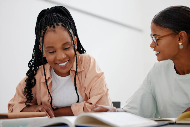 Black woman, education and learning with books on table with girl, tutor or teacher. Friends, students and study together at desk with notebook for college, university or school while home in Phoenix. - Photo, image
