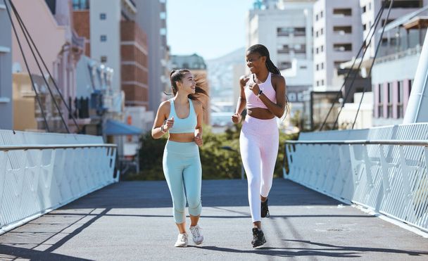 Health women and friends running on bridge in city together for workout and exercise lifestyle. Girl friendship with young, happy and athletic people enjoying cardio fitness run in urban town - Photo, image