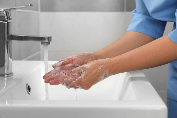 Doctor washing hands with water from tap in bathroom, closeup - Zdjęcie, obraz