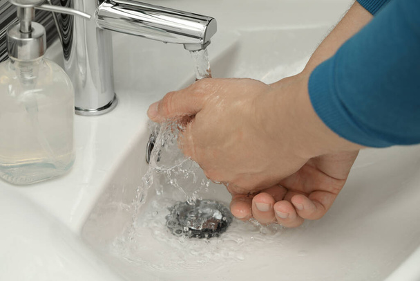 Man using water tap to wash hands in bathroom, closeup - Fotoğraf, Görsel