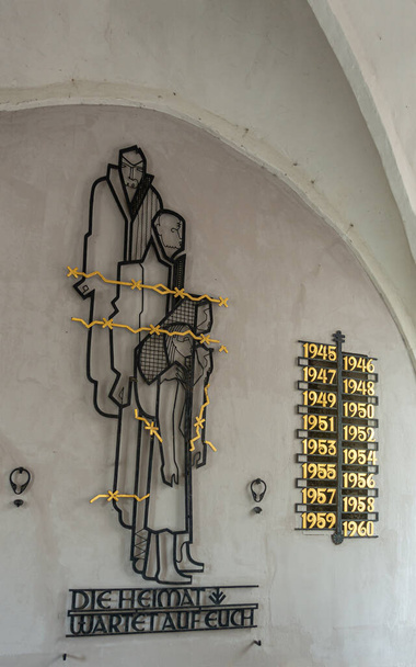 ドイツ、ルベック- 2022年7月13日:第二次世界大戦中に捕虜となり、戦後何年もソ連で捕虜となったドイツ人捕虜のための記念碑。白い壁に対する芸術の金と黒の金属片 - 写真・画像