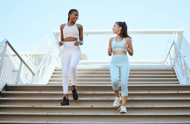 Fitness women, running steps and exercise for healthy lifestyle, wellness and marathon training in urban city outdoors. Happy athletes, runners and friends cardiovascular workout down stairs together. - Foto, immagini
