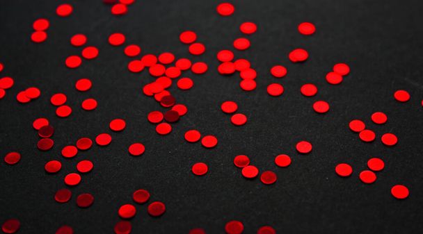 Vibrant glowing red metallic circle confetti decoration on a black background. Glitter. Festive backdrop. Template. - 写真・画像