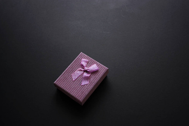 Violett glänzende Geschenkschachtel auf schwarzem Hintergrund. - Foto, Bild