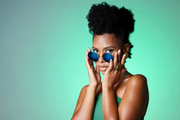 Portrait of trendy black woman in green background with sunglasses. Mockup for natural beauty, fashion and makeup in spring or summer. Black model in funky glasses, modern style in the studio. - Foto, Imagem