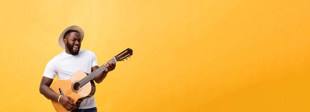 Όμορφος αφρικανική αμερικανική ρετρό στυλ κιθαρίστας παίζει ακουστική κιθάρα που απομονώνονται σε κίτρινο φόντο - Φωτογραφία, εικόνα