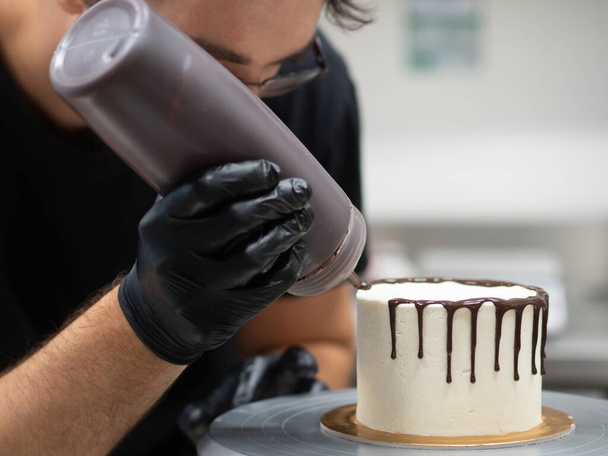 nierozpoznawalny pracownik przygotowujący słodkie kapanie ciasta czekoladowego i jagód - Zdjęcie, obraz