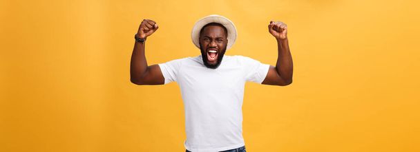Werknemer van het gevoel van opgewonden, knappe jonge Afro-Amerikaanse man, gebaren actief, vuisten gebalde, riep vreugde met de mond wijd geopend, tevreden met geluk of promotie op het werk te houden. - Foto, afbeelding