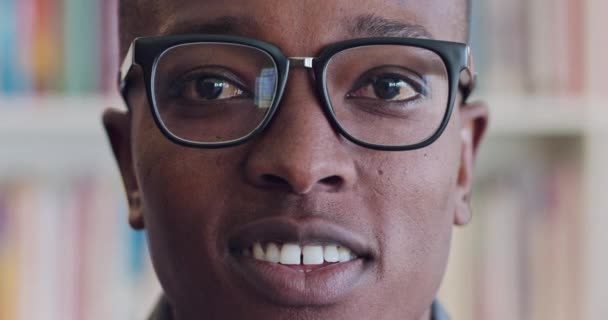 Man, smile and macro portrait of face with glasses, in library or bookstore, with author or librarian. Black man, happy and zoom of happy laugh in Chicago, joy and writer with background of bookshelf. - Footage, Video
