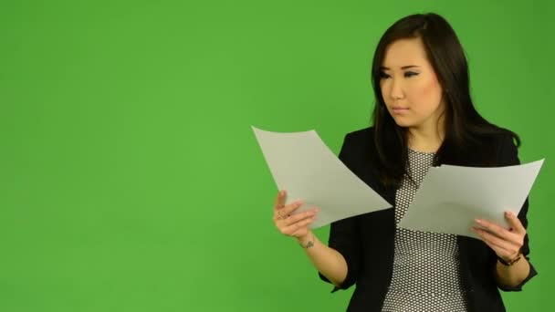 Jonge aantrekkelijke Aziatische vrouw leest documenten (papieren) - groen scherm studio - Video