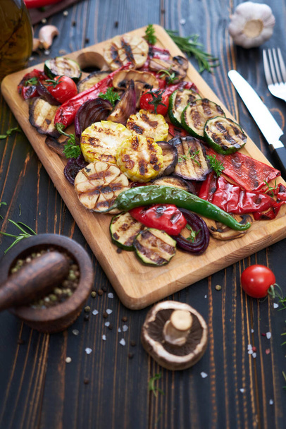 Grilled vegetables mix on a wooden cutting board - zucchini eggplant onions corn mushroom tomato. - Фото, изображение