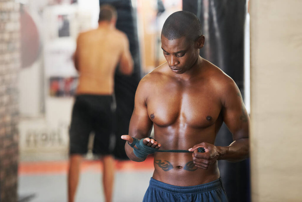 Vorsichtshalber. Ein afrikanisch-amerikanischer Boxer klebt seine Hände im Fitnessstudio zusammen - Foto, Bild