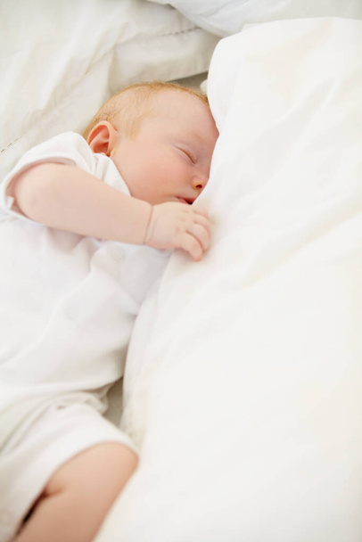 This little girl needs her sleep. A baby girl fast asleep in between her white pillows - Foto, afbeelding