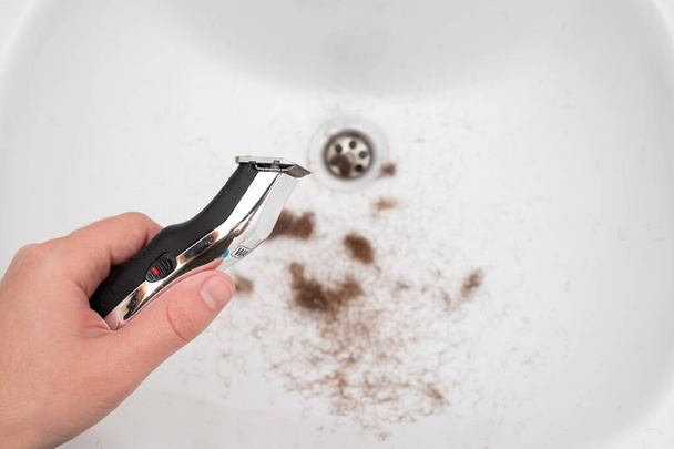 Чоловік тримає електричну бороду тример після гоління бороду з тримером для стрижки волосся
. - Фото, зображення
