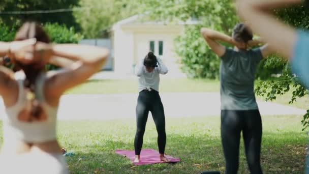 Gruppo di giovane donna sportiva che pratica lezione di yoga con istruttore nel parco - Filmati, video