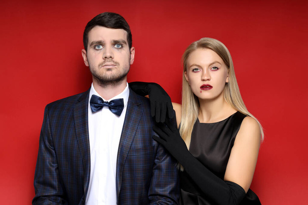 Concept of Halloween, young man and woman on red background - Photo, Image