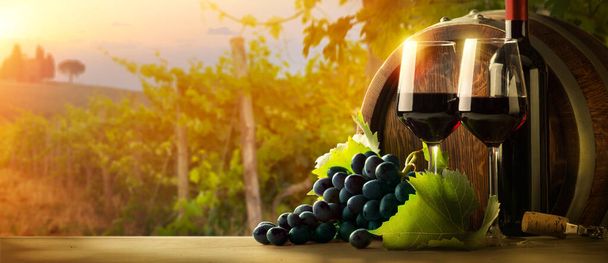 Botella de vino tinto, copa de vino y barril de madera. Hermosa Italia fondo del viñedo Toscana - Foto, imagen