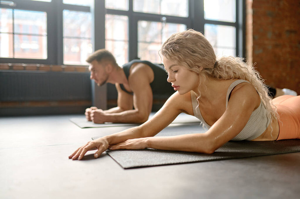 Fitness feminino e masculino exercitando-se no ginásio. Homem e mulher fazendo exercícios abdominais na aula de treinamento em grupo - Foto, Imagem