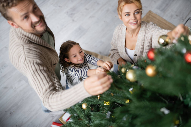 Vue grand angle de la famille souriante décorer arbre de Noël à la maison  - Photo, image
