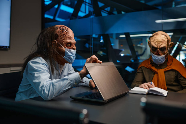 Zombie hombres de negocios con máscara de la cara charlando en la conferencia de negocios. Reunión de trabajo durante el concepto de pandemia - Foto, Imagen