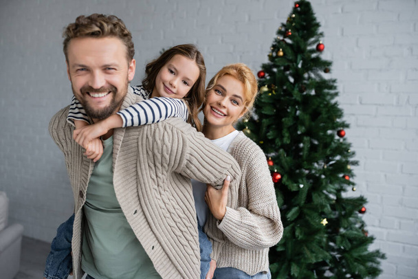 幸せな家族抱擁し、自宅でクリスマスのお祝い中にカメラを見て  - 写真・画像