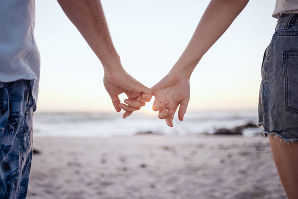Liebe, Paar und Händchenhalten an Strand und Sand für Beziehung, Jubiläum und Umarmung während des gemeinsamen Urlaubs. Romantik, Mann und Frau glücklich, liebevoll und verbindend mit Sonnenuntergang im Urlaub und auf Reisen. - Foto, Bild
