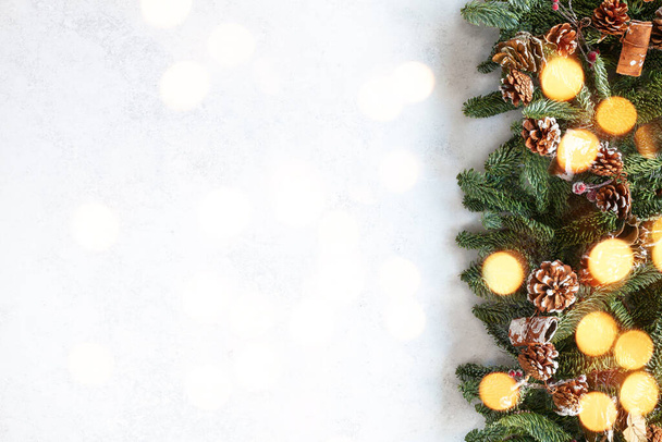 Christmas background with fir branches, pine cones and bokeh lights on a white background. Holiday card with space for text. Merry Christmas and Happy New Year! - Foto, immagini