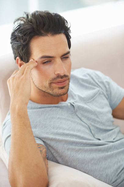 Migraine matinale. Un jeune homme magnifique couché sur un canapé avec la tête posée sur sa main - Photo, image