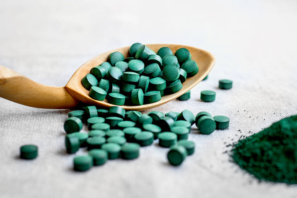 Greeodenn seaweed spirulina in tablets and powder on a burlap background. Top view. Vegetable protein - Foto, imagen