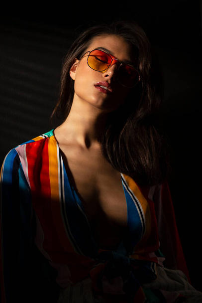 Przód portretu młodej zmysłowej kobiety w kolorowym top i okularach przeciwsłonecznych. - Zdjęcie, obraz