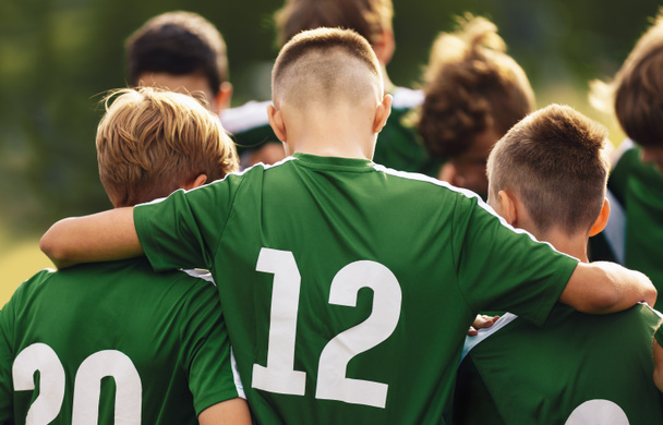 Teenage boys freindship in a sports team. Group of sports players huddling in a circle and motivating each other. Boys in green jersey shirts with numbers - Photo, Image