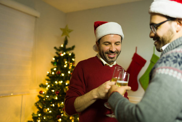 Nagyon boldog meleg pár pohárköszöntőt mond, bort isznak és mosolyognak, miközben együtt ünneplik a karácsonyi ünnepeket. - Fotó, kép