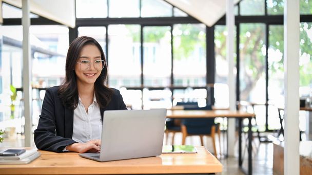 Atraktivní mladá asijská podnikatelka nebo manažerka marketingu pracuje na svém projektu, pomocí notebooku, zatímco sedí v kavárně spolupracuje prostor. - Fotografie, Obrázek