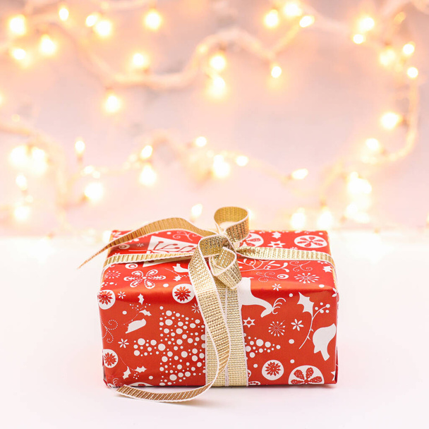 Red Christmas gift with golden ribbon with lights on background. New year concept - Photo, Image