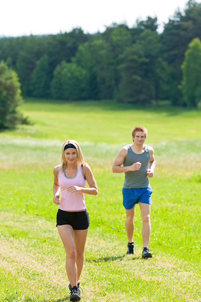 Sportive young couple jogging meadows sunny summer - Фото, изображение