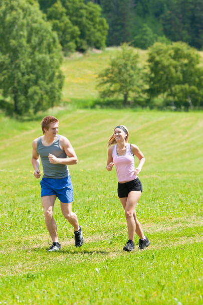 Sportive young couple jogging meadows sunny summer - Foto, imagen