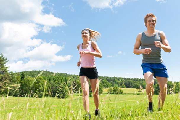 Sportive young couple jogging meadows sunny summer - Foto, immagini