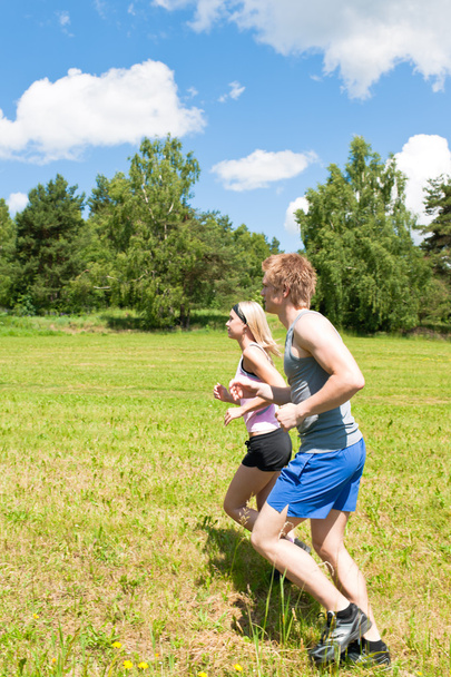 Sportive young couple jogging meadows sunny summer - Valokuva, kuva